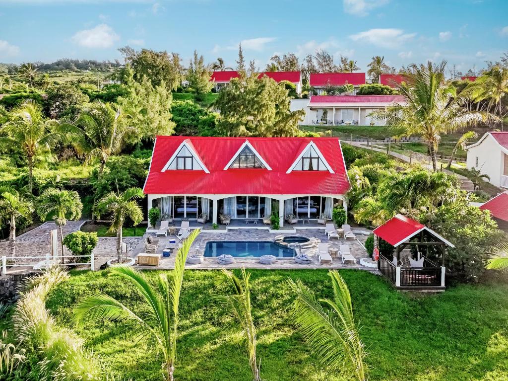 Villa avec piscine privée au cœur d’un jardin tropical, toit rouge typique et terrasse aménagée.
