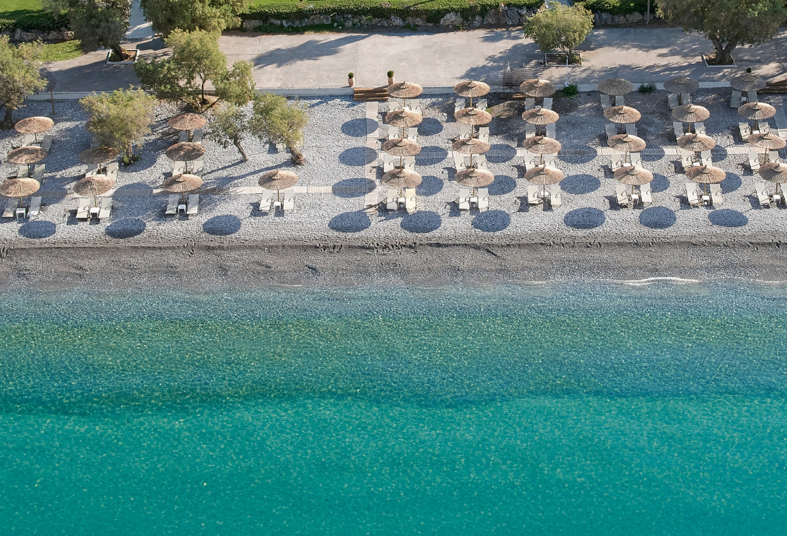 http://Rangée%20de%20transats%20sous%20des%20parasols%20en%20paille%20sur%20une%20plage%20grecque