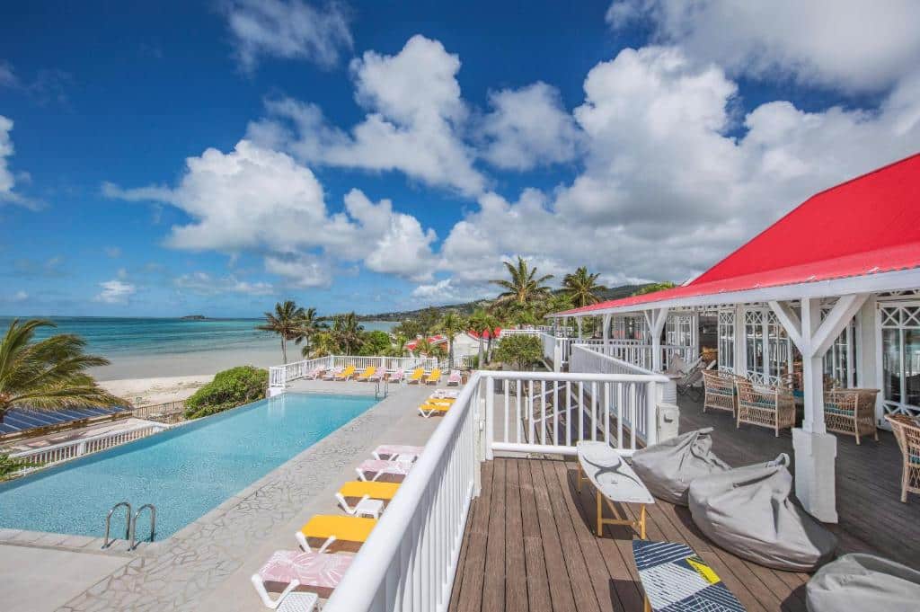 http://Piscine%20à%20débordement%20sur%20une%20terrasse%20en%20bois,%20bordée%20de%20transats%20colorés,%20avec%20vue%20sur%20la%20mer%20et%20accès%20direct%20à%20la%20plage.