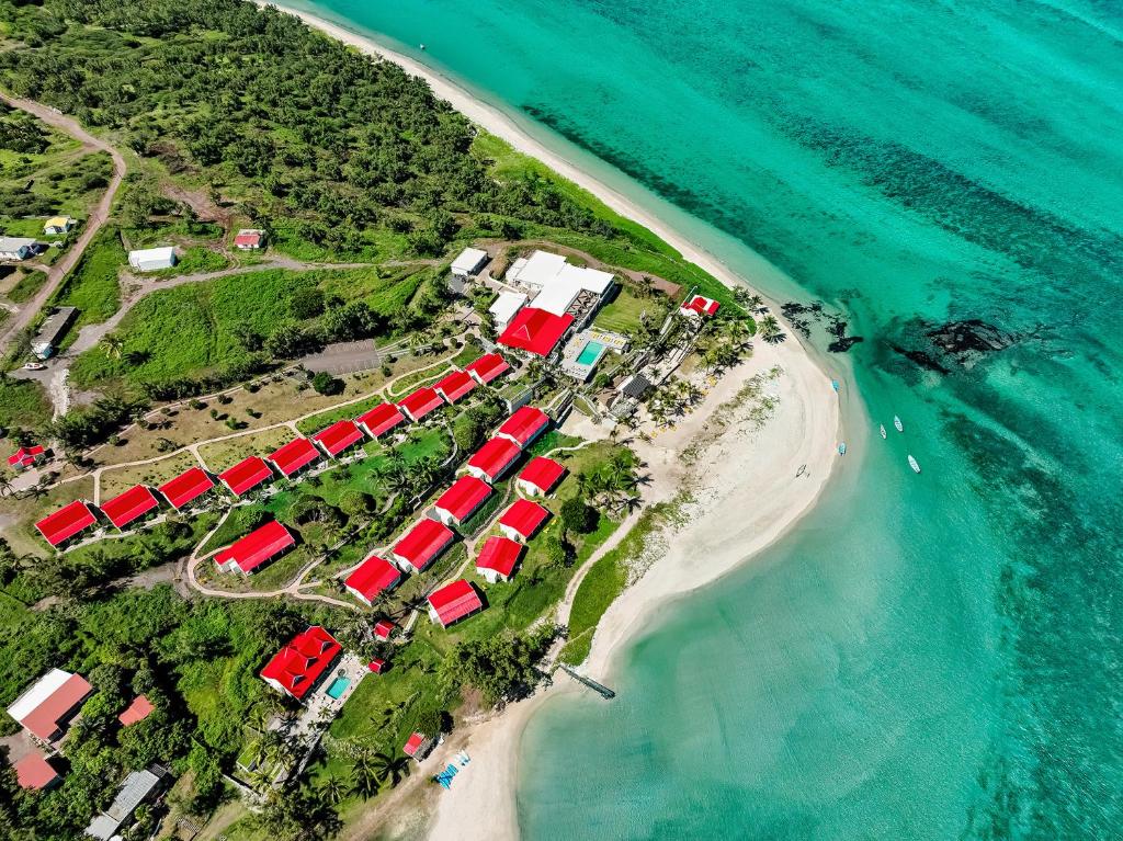 http://Vue%20aérienne%20d’un%20hôtel%20avec%20toits%20rouges%20situé%20en%20bord%20de%20plage,%20entouré%20de%20nature%20tropicale%20et%20d’eau%20turquoise.