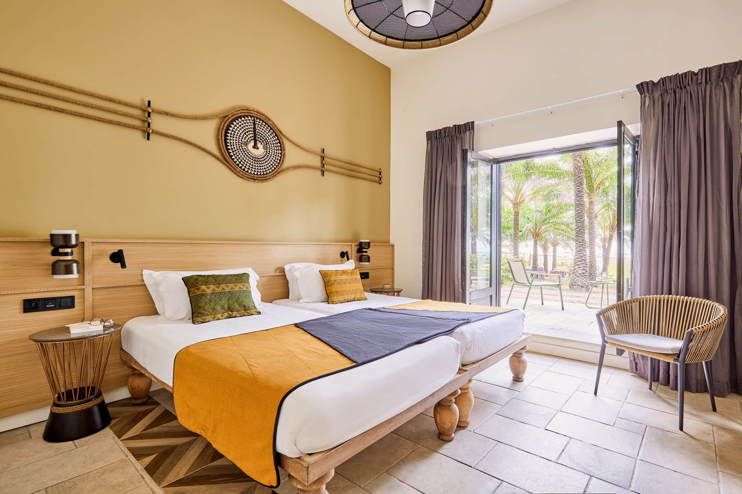 http://Chambre%20d’hôtel%20avec%20deux%20lits%20simples,%20déco%20naturelle%20et%20terrasse%20donnant%20sur%20un%20jardin%20tropical