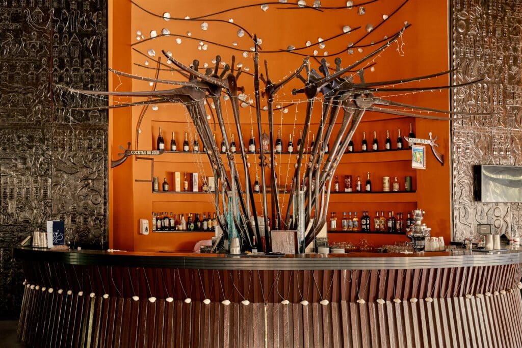 Bar décoré de sculptures métalliques en forme d’oiseaux devant un mur orange