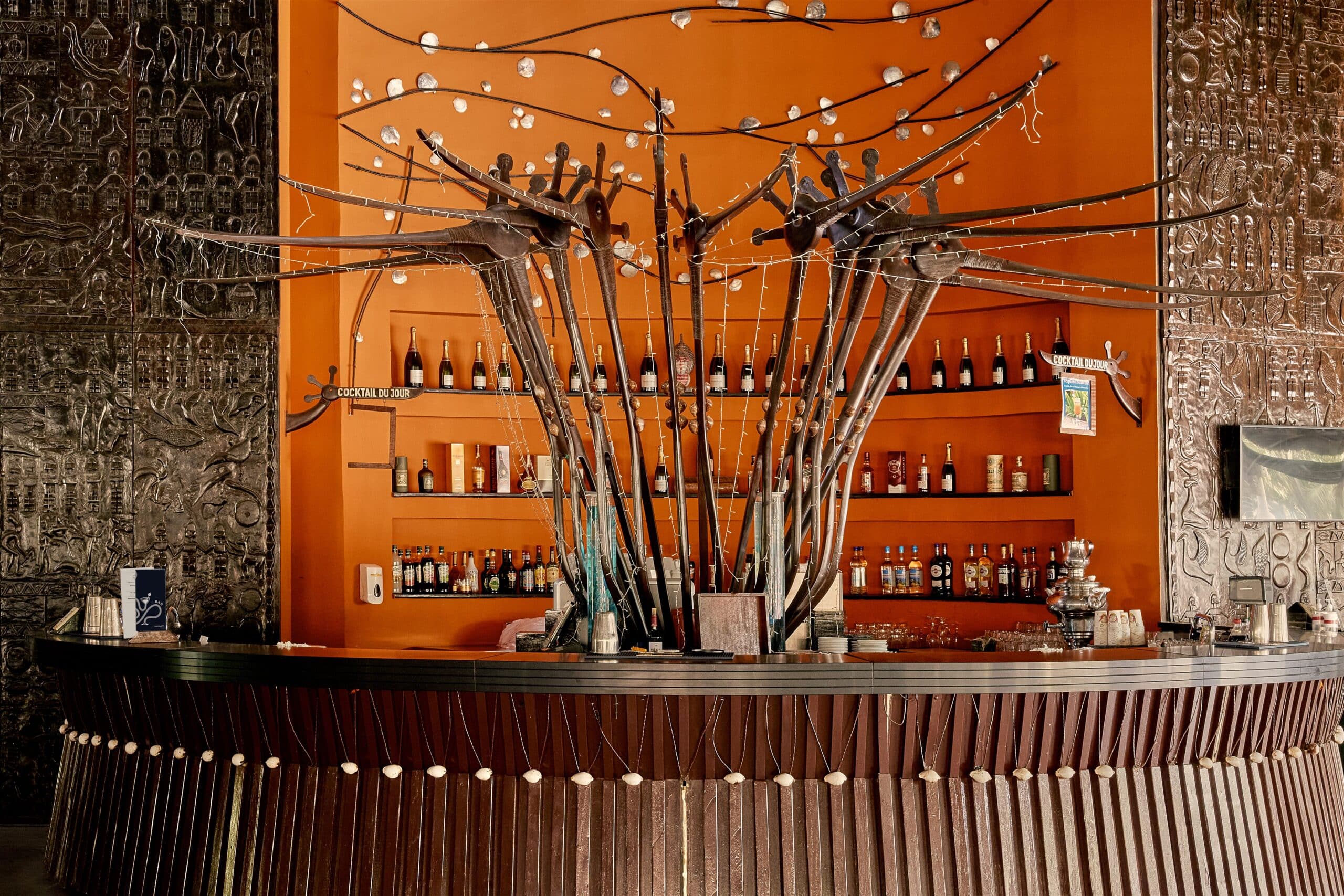 http://Bar%20décoré%20de%20sculptures%20métalliques%20en%20forme%20d’oiseaux%20devant%20un%20mur%20orange