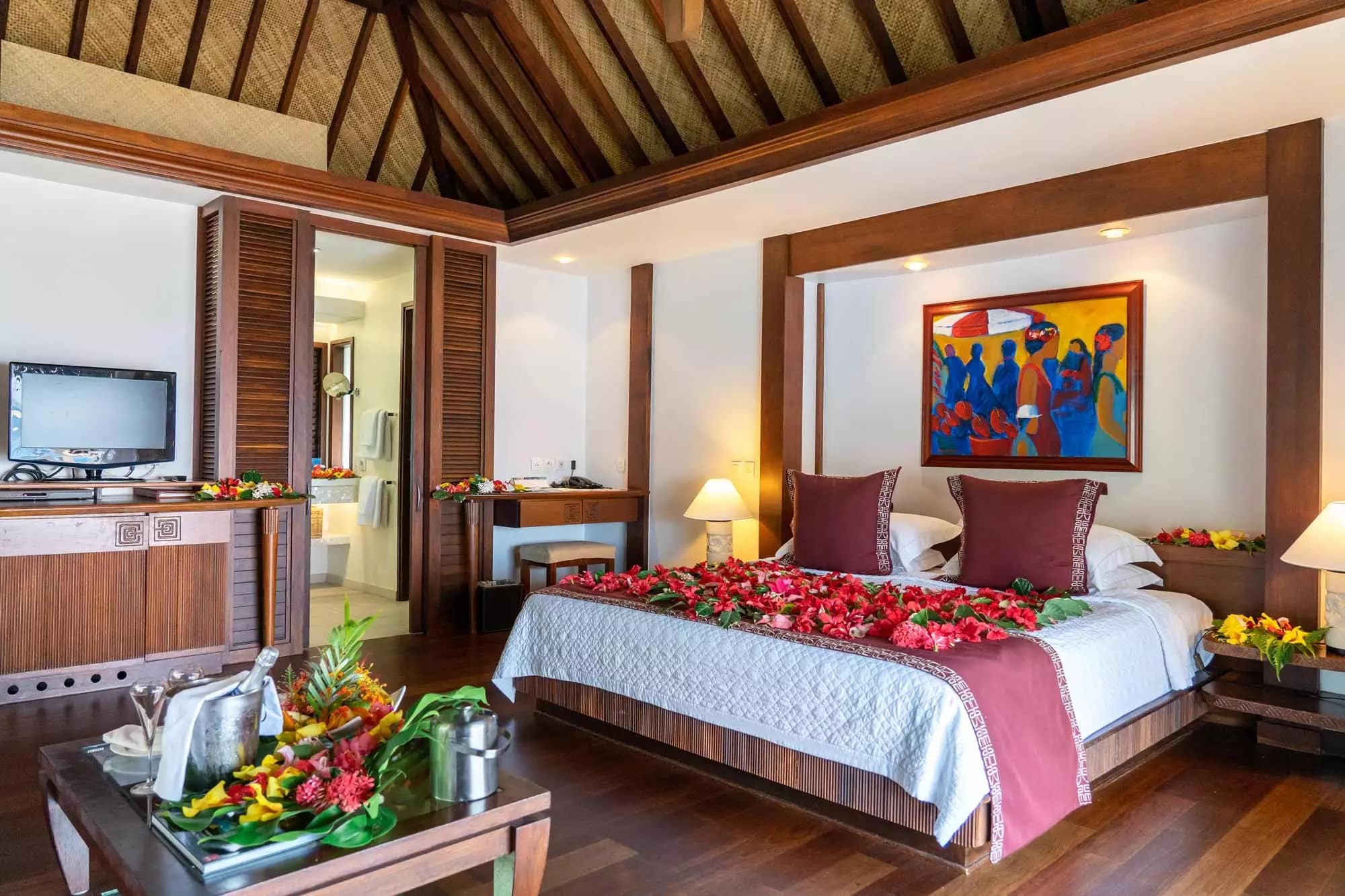 http://Chambre%20de%20bungalow%20en%20bois%20avec%20lit%20décoré%20de%20fleurs%20exotiques,%20dans%20un%20hôtel%20polynésien.