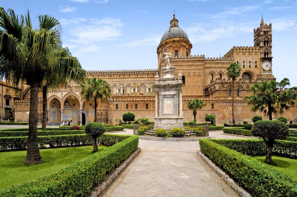 La cathédrale de Palerme en Sicile, entourée de jardins bien entretenus et de statues baroques.
