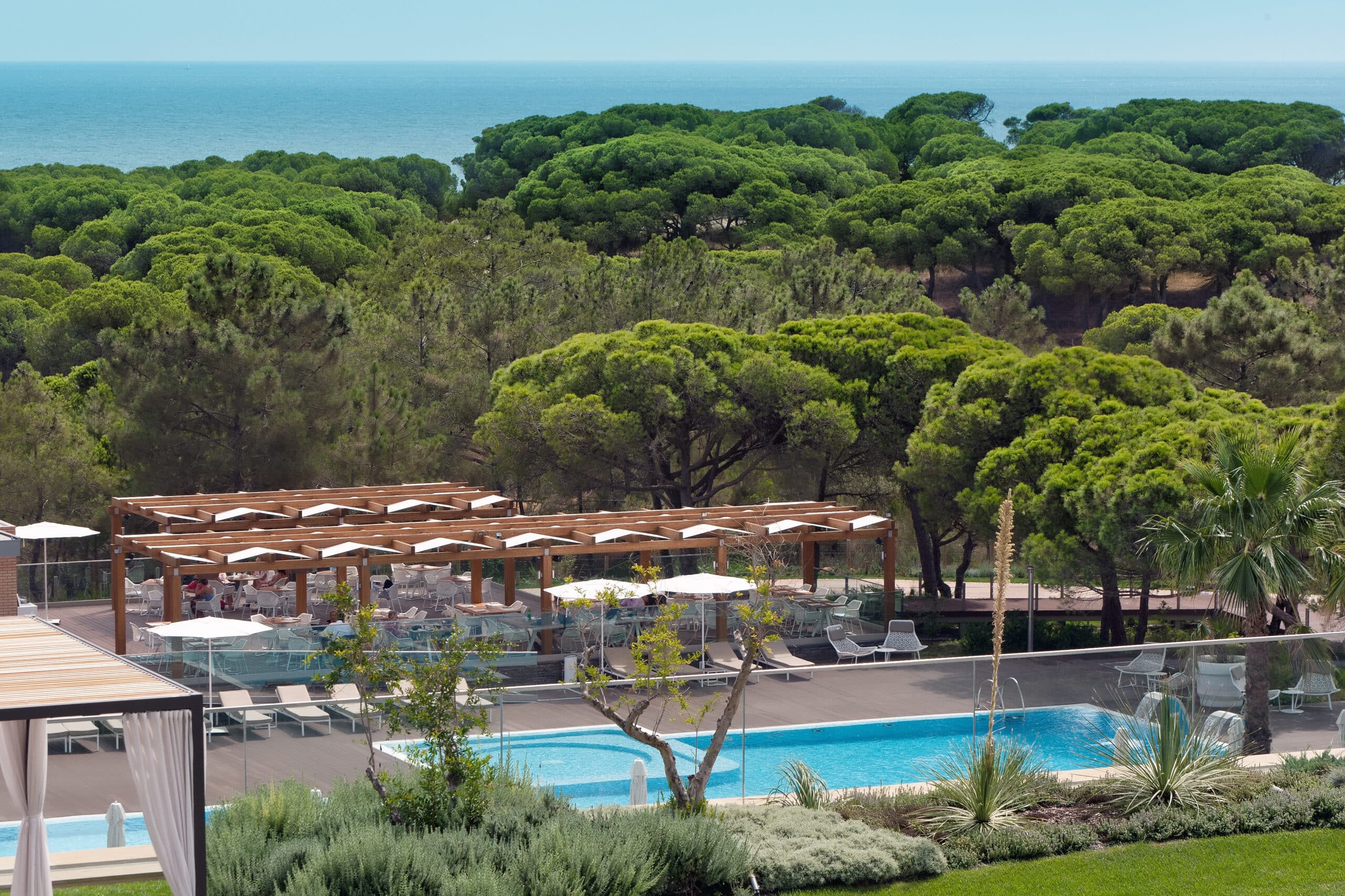 http://Piscine%20extérieure%20avec%20vue%20sur%20la%20pinède%20et%20l’océan%20dans%20un%20complexe%20hôtelier%20de%20luxe.