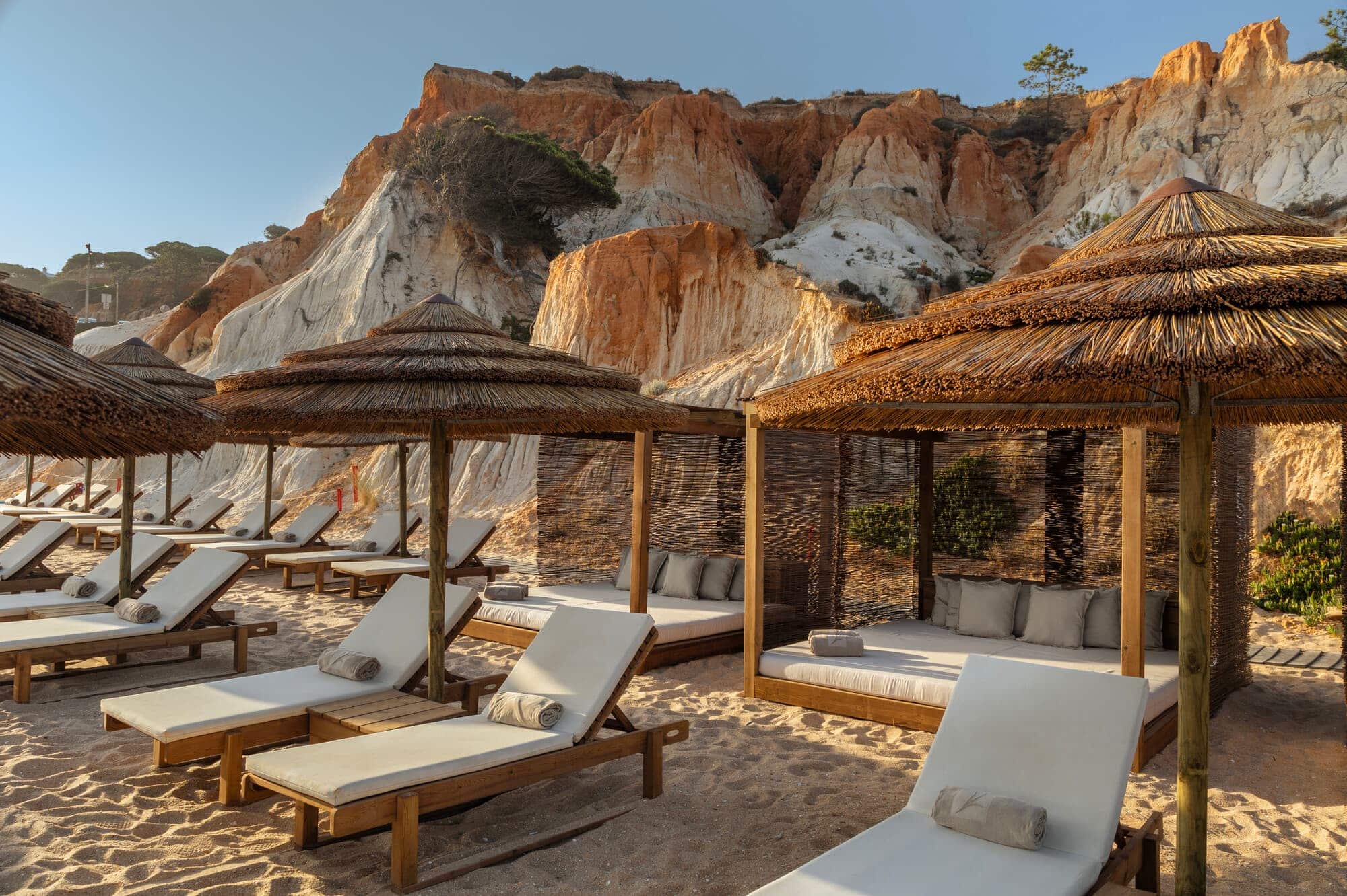 http://Transats%20en%20bois%20et%20parasols%20en%20paille%20sur%20une%20plage%20aux%20falaises%20rouges%20et%20blanches.