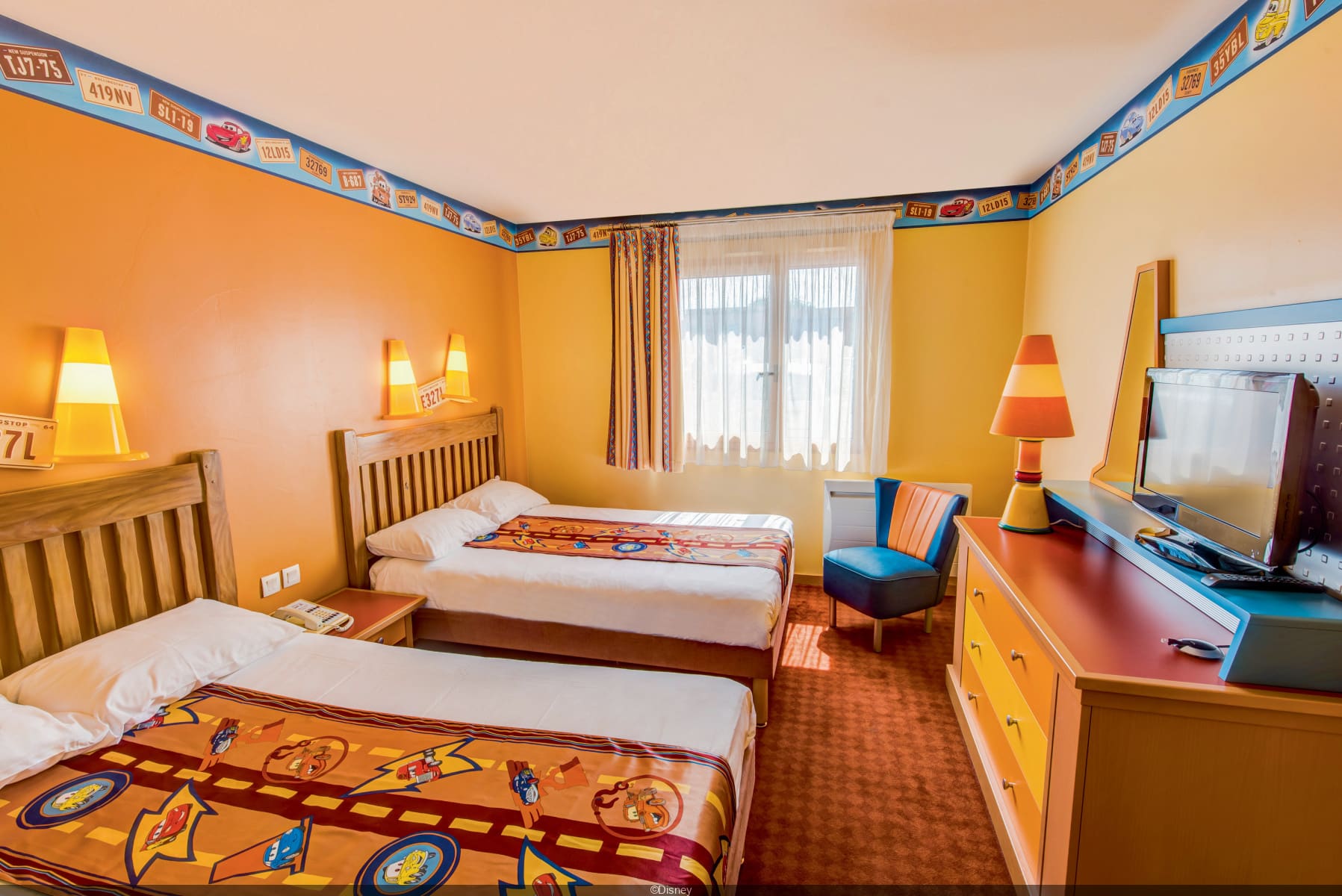 http://Chambre%20d’hôtel%20décorée%20sur%20le%20thème%20Cars%20avec%20deux%20lits%20simples%20et%20décoration%20colorée%20à%20Disneyland%20Paris