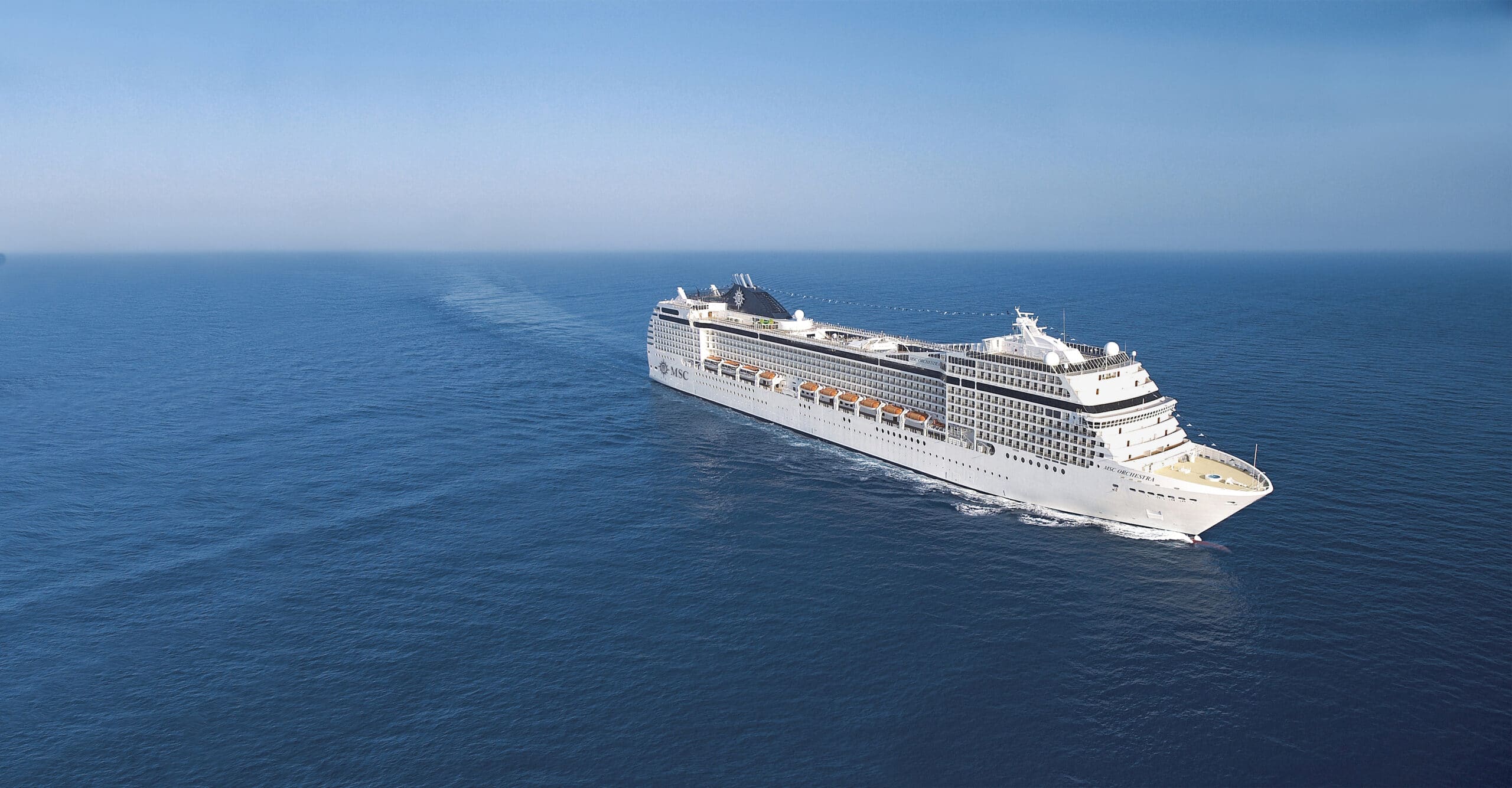 Vue aérienne du navire de croisière MSC Orchestra naviguant sur une mer bleue sous un ciel dégagé.