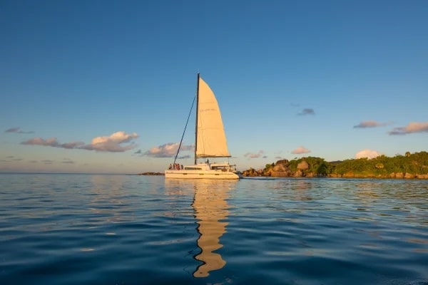 Catamaran naviguant au coucher du soleil dans les eaux paisibles des Seychelles