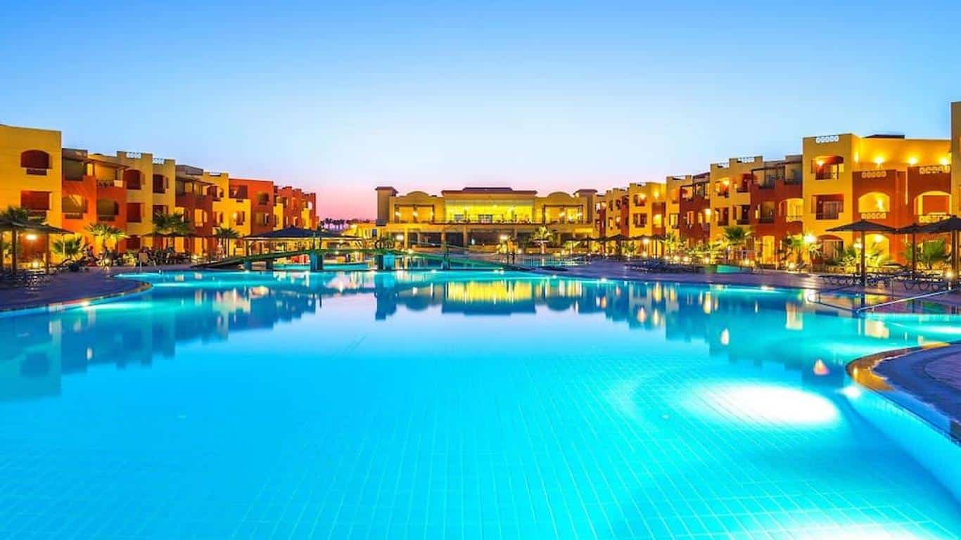 http://Piscine%20extérieure%20illuminée%20entourée%20de%20bâtiments%20colorés%20au%20coucher%20du%20soleil.