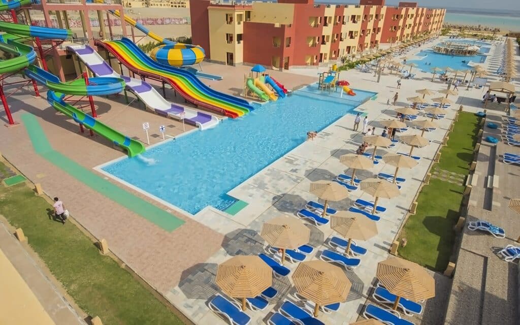 Parc aquatique avec toboggans colorés, piscines et transats dans un complexe hôtelier en Égypte.