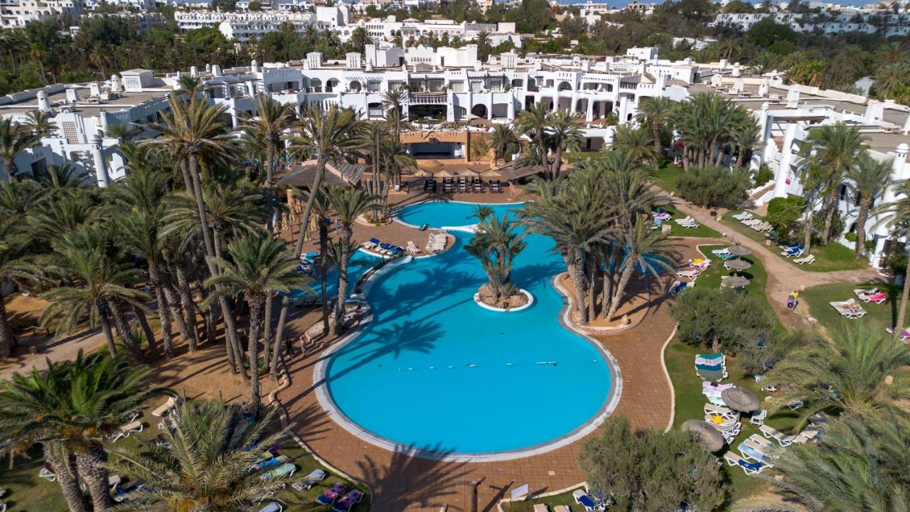 http://Grande%20piscine%20extérieure%20bordée%20de%20palmiers%20au%20cœur%20d’un%20hôtel%20de%20style%20andalou%20à%20Djerba.