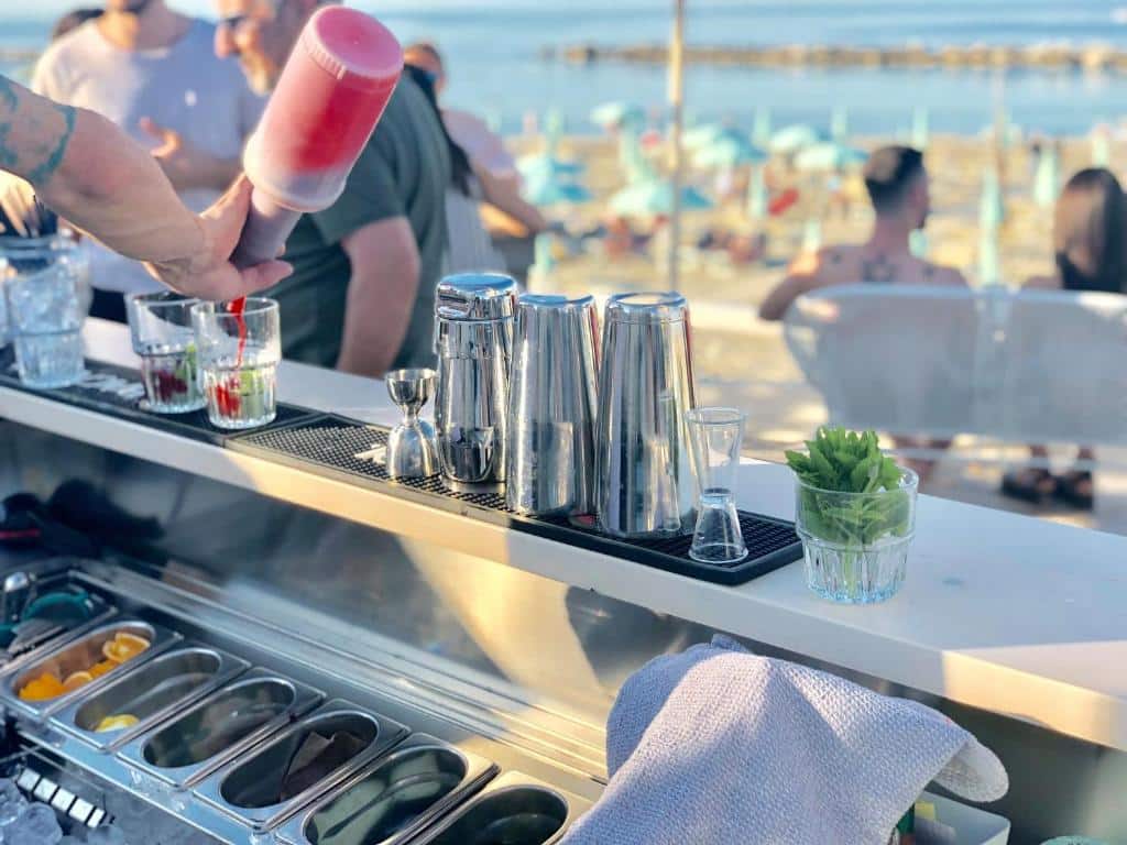 http://Barman%20préparant%20un%20cocktail%20au%20bar%20de%20plage%20avec%20vue%20sur%20la%20mer%20et%20transats.