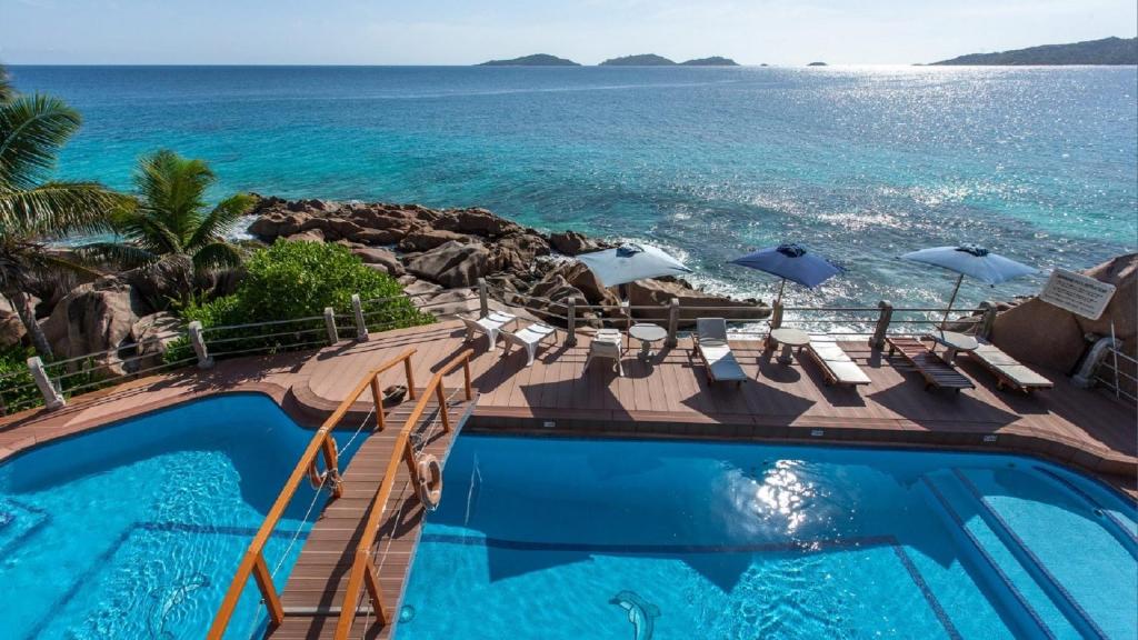 http://Piscine%20d’hôtel%20face%20à%20la%20mer%20avec%20transats%20et%20parasols%20aux%20Seychelles