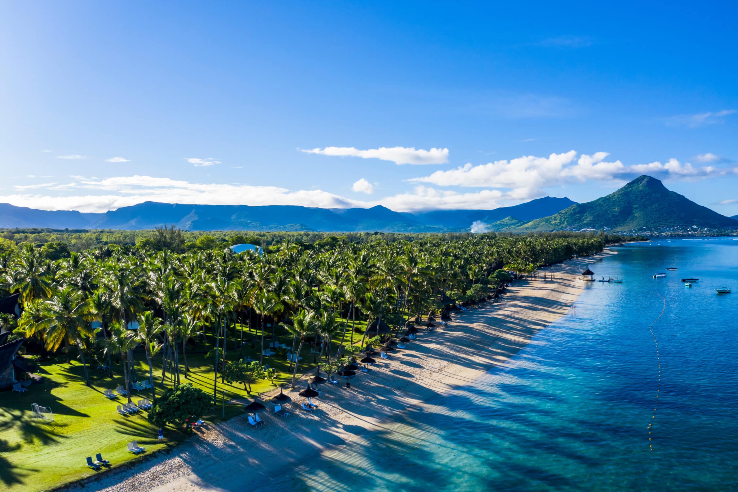 http://Vue%20aérienne%20d’une%20plage%20bordée%20de%20cocotiers%20et%20de%20montagnes%20à%20l’île%20Maurice