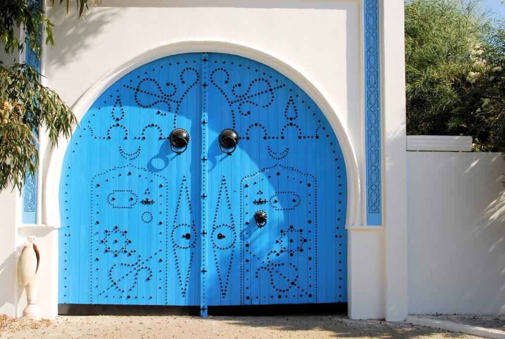Porte traditionnelle tunisienne bleue avec motifs en clous noirs à Sidi Bou Saïd