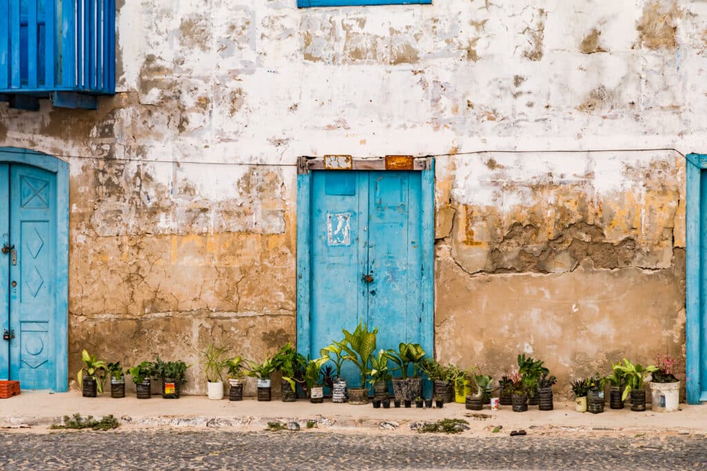 Vieille façade de maison à portes bleues avec pots de plantes à São Vicente