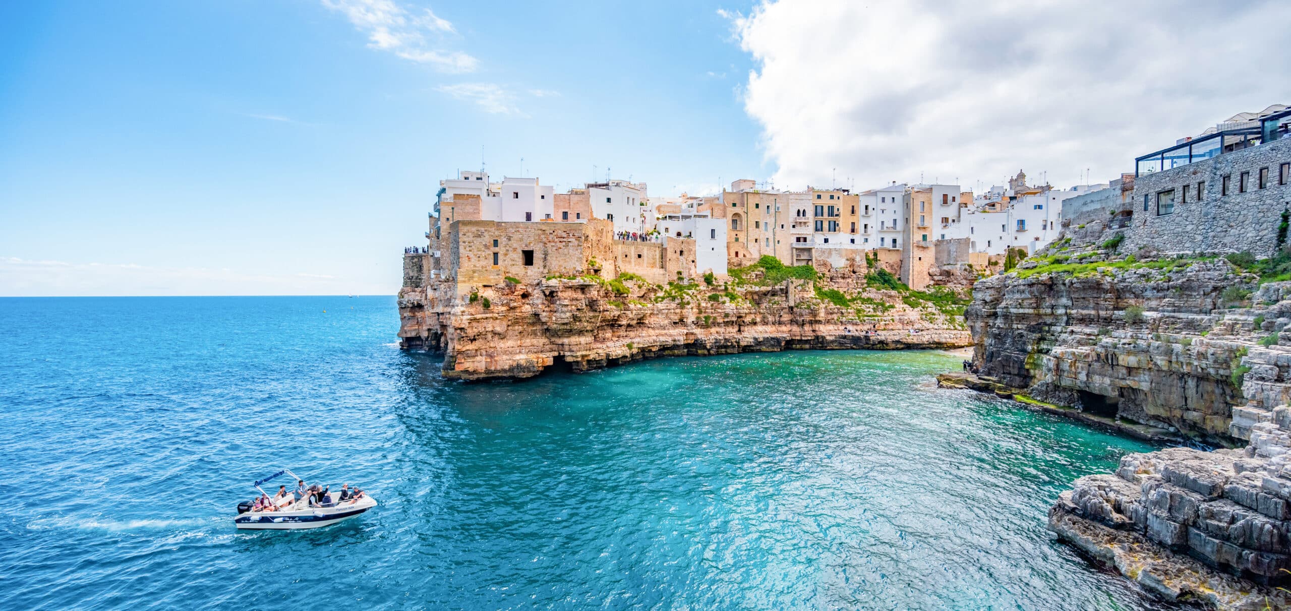 http://Falaises%20et%20maisons%20blanches%20de%20Polignano%20a%20Mare%20surplombant%20la%20mer%20Adriatique%20avec%20un%20bateau%20de%20touristes.
