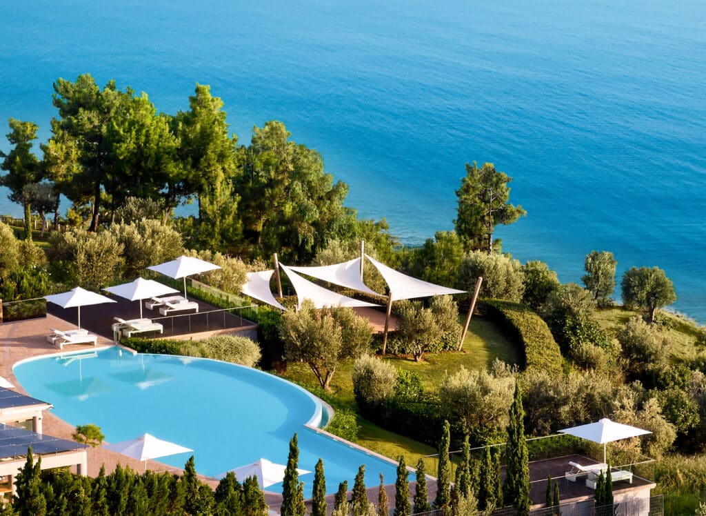 Piscine et jardin avec tonnelles blanches donnant sur la mer depuis un hôtel
