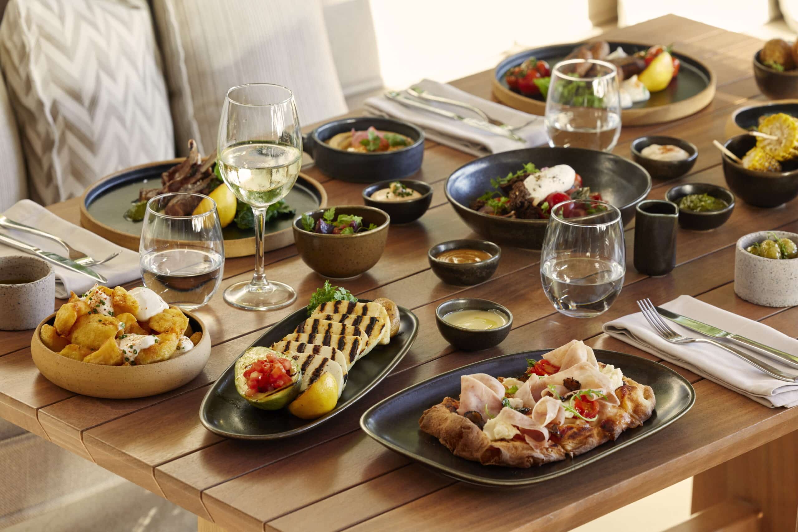 http://Table%20de%20restaurant%20avec%20assortiment%20de%20plats%20méditerranéens%20et%20verres%20de%20vin%20blanc