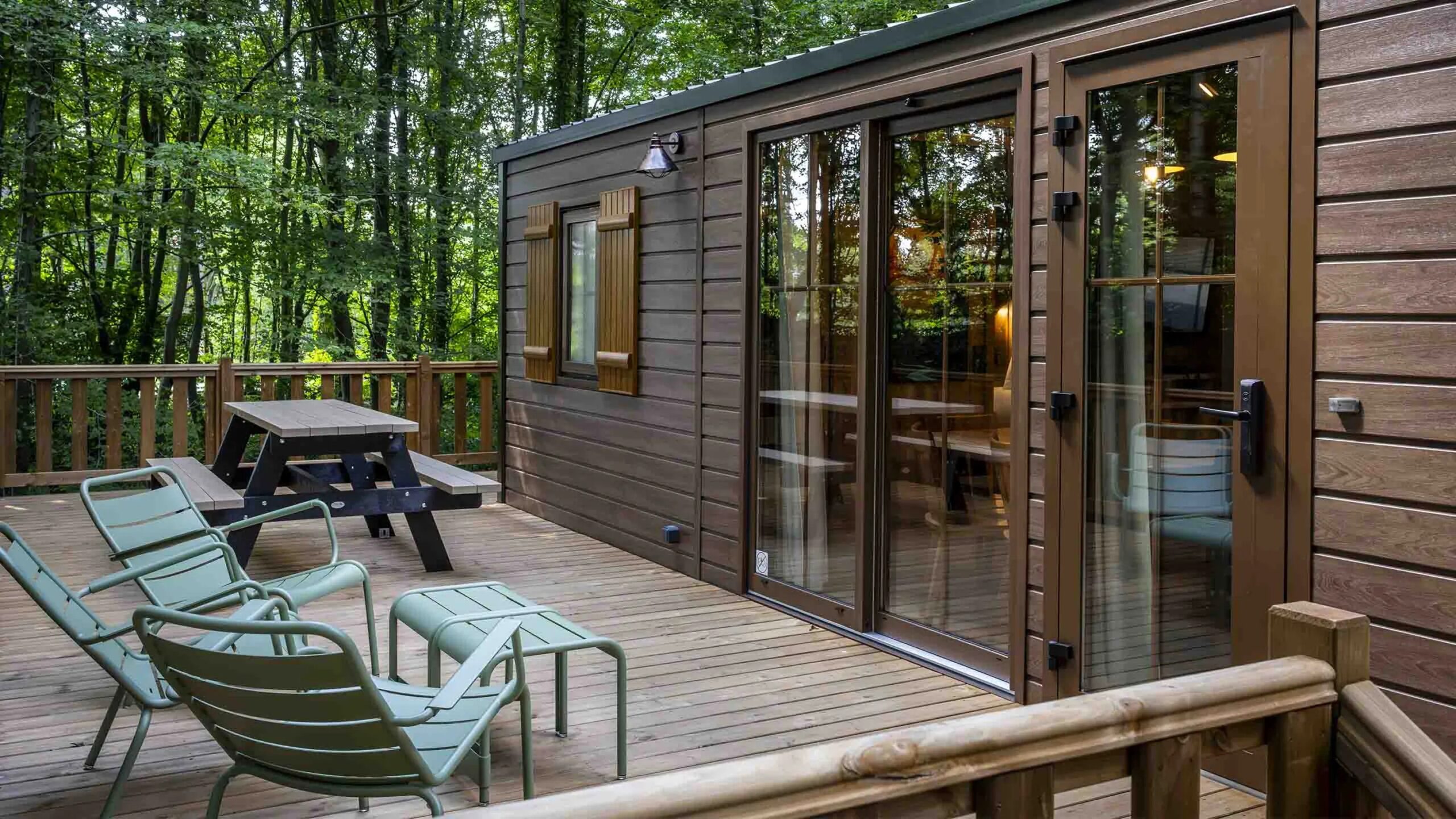 http://Terrasse%20en%20bois%20d’un%20bungalow%20avec%20salon%20de%20jardin,%20au%20cœur%20d’une%20forêt%20verdoyante.
