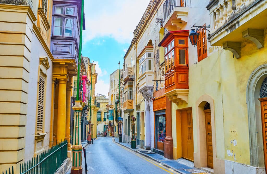 Rue typique de La Valette avec maisons anciennes et balcons maltais colorés.