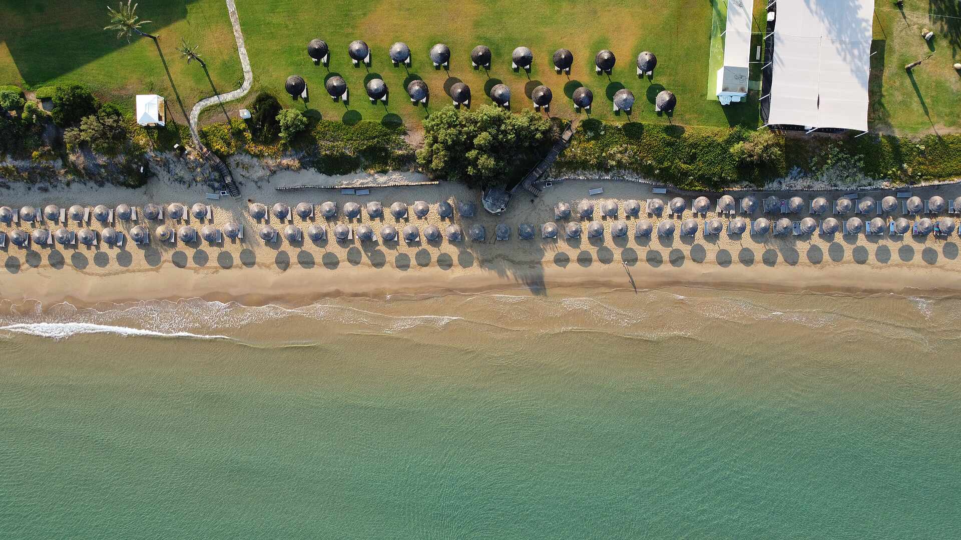 http://Alignement%20de%20parasols%20sur%20une%20plage%20de%20sable%20doré%20vue%20du%20ciel%20avec%20mer%20calme.