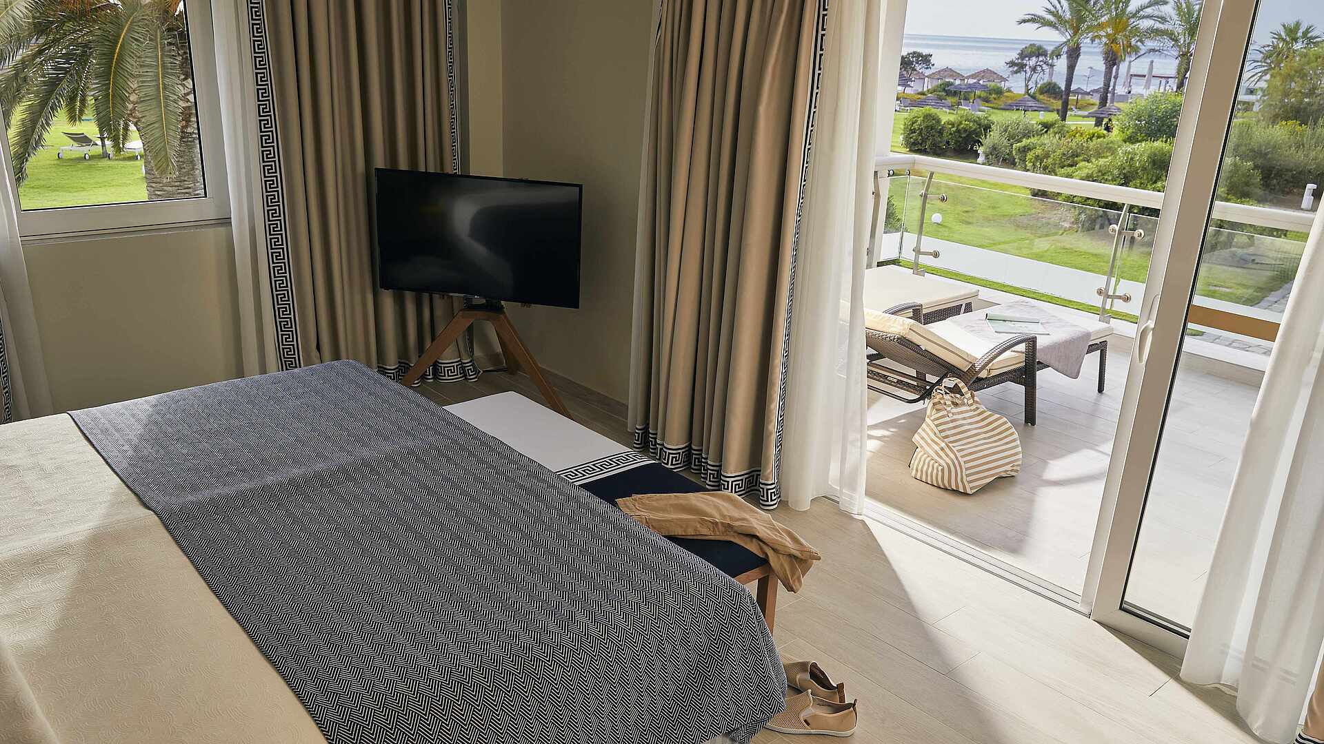 http://Chambre%20d’hôtel%20avec%20balcon%20privatif,%20transat%20et%20vue%20sur%20les%20palmiers%20et%20la%20mer.