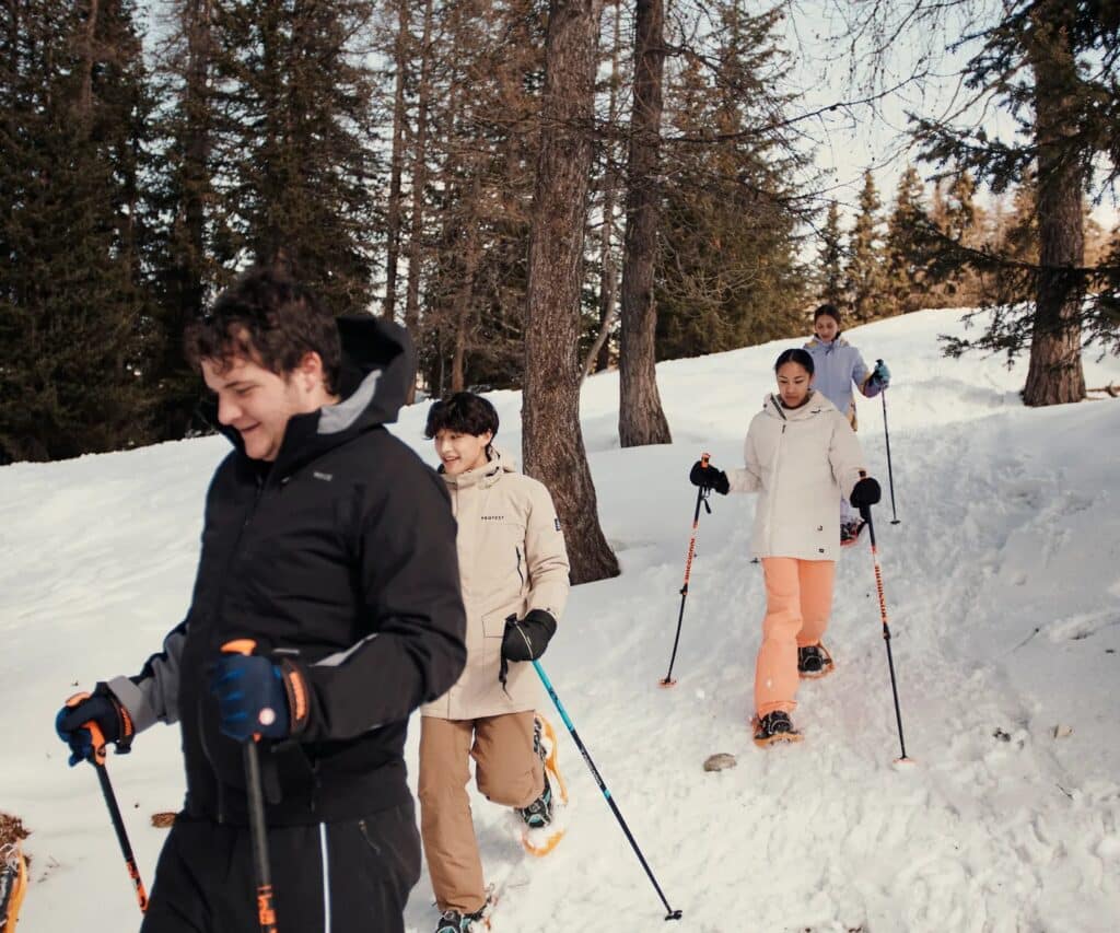 Groupe de personnes en randonnée raquettes dans une forêt enneigée en hiver