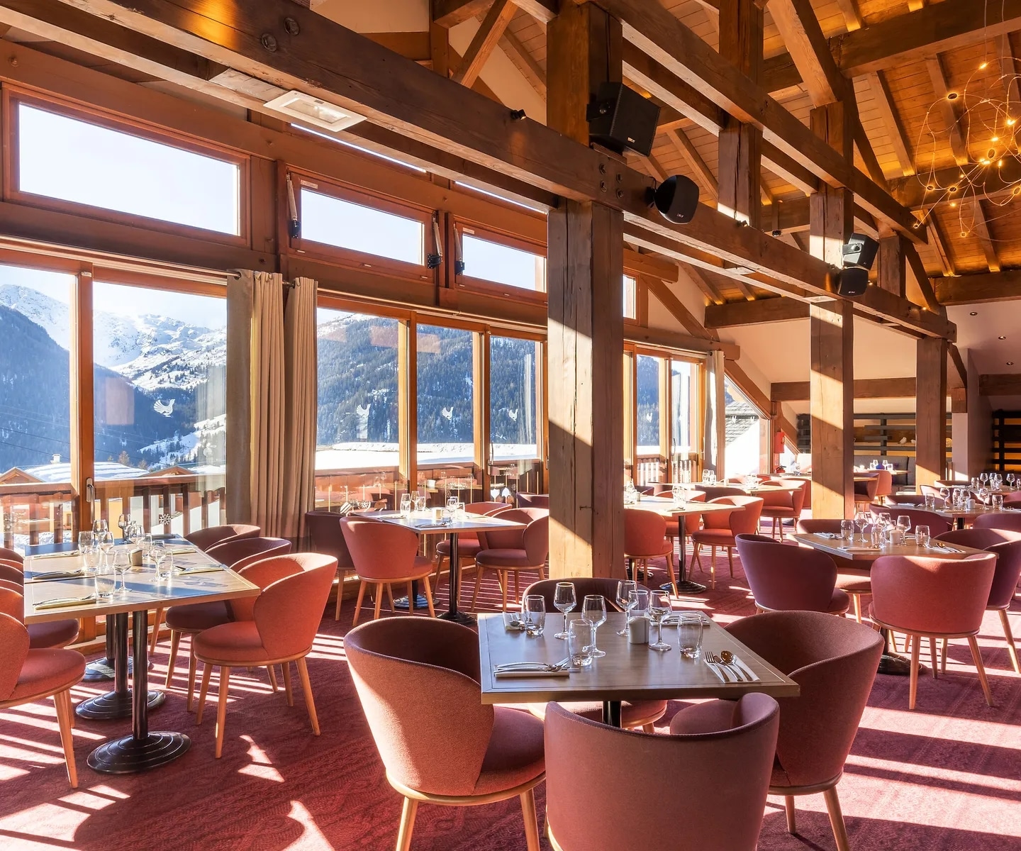 http://Salle%20de%20restaurant%20en%20bois%20avec%20grandes%20fenêtres%20et%20vue%20sur%20les%20montagnes%20enneigées