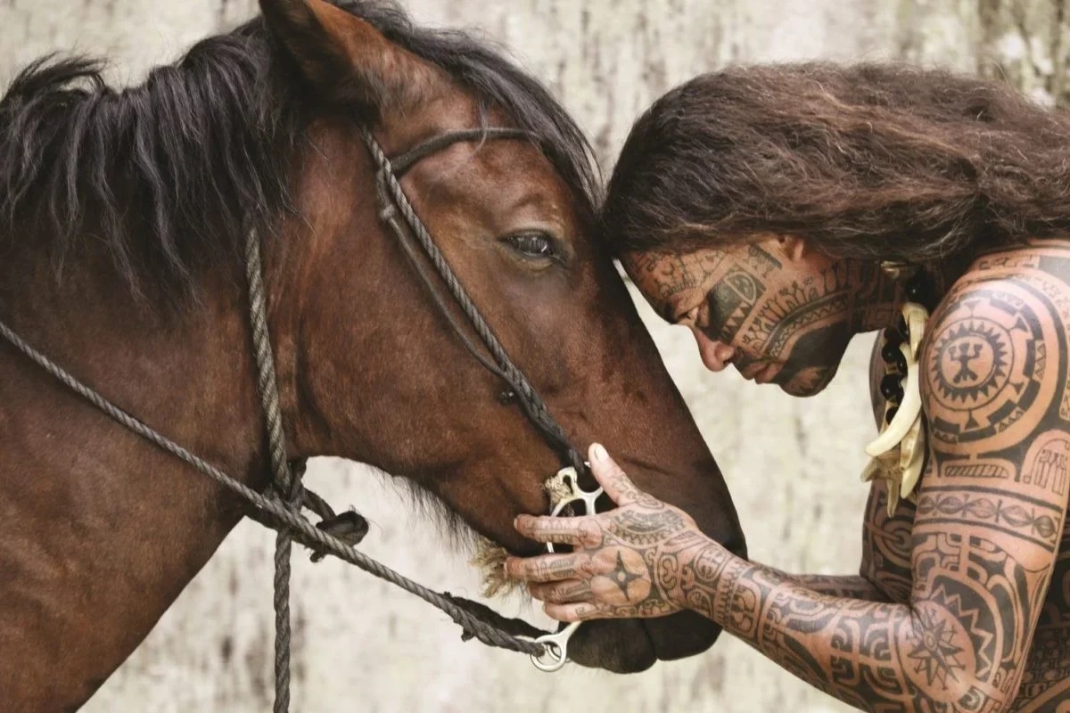 http://Homme%20aux%20tatouages%20traditionnels%20caressant%20un%20cheval%20en%20Polynésie