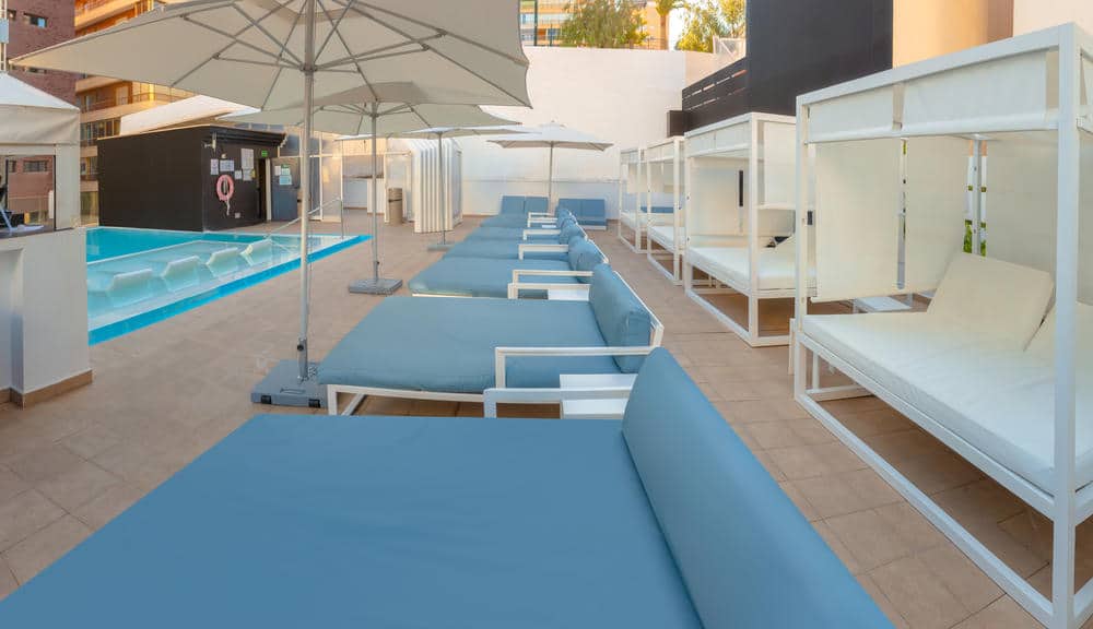 http://Piscine%20d’hôtel%20avec%20transats%20et%20lits%20balinais%20dans%20un%20espace%20moderne