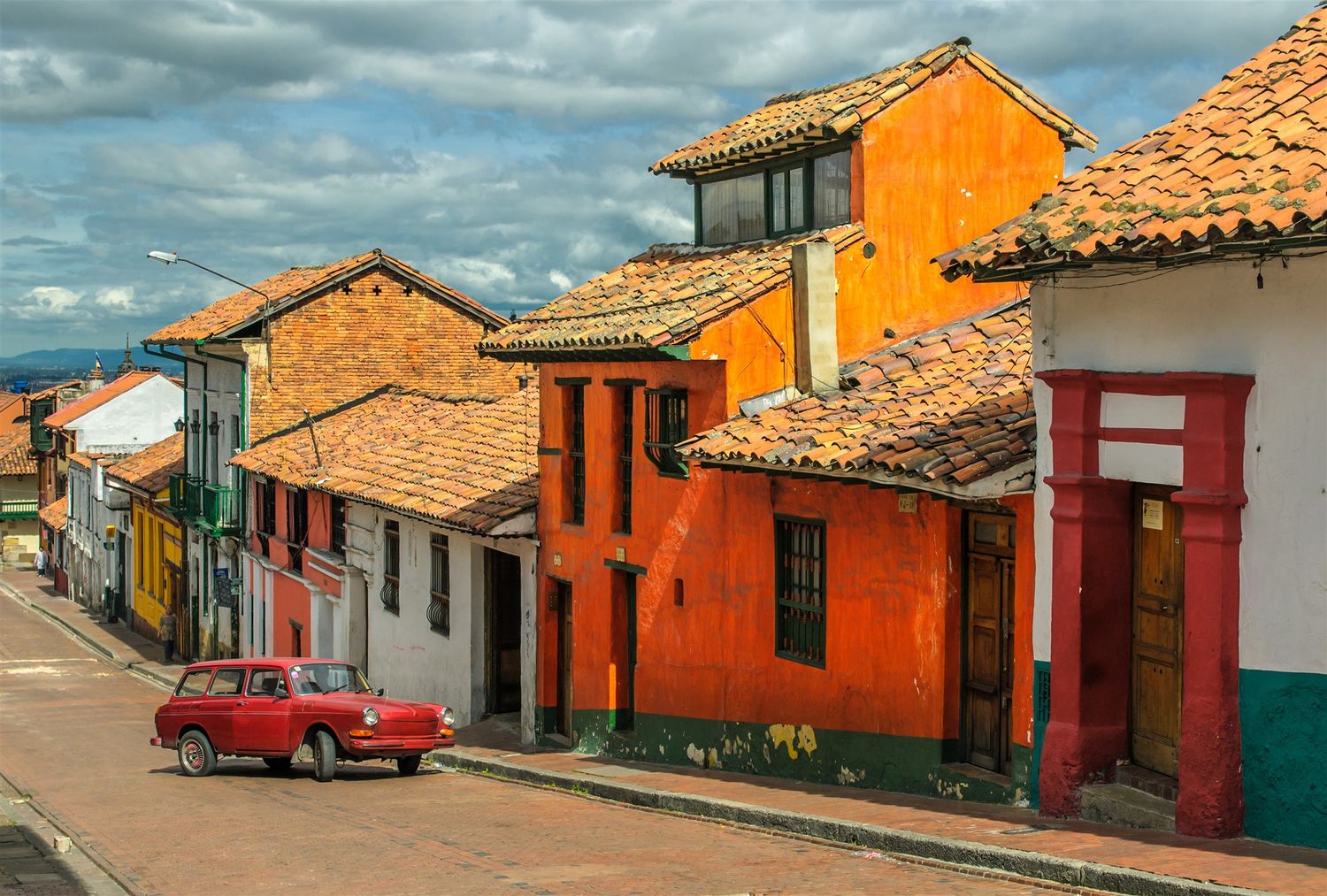 http://Rue%20pavée%20avec%20maisons%20colorées%20et%20voiture%20vintage%20en%20Colombie