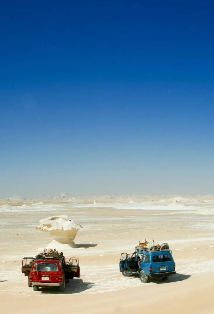 http://Deux%20véhicules%204x4%20dans%20le%20désert%20blanc%20avec%20formations%20rocheuses%20et%20ciel%20bleu