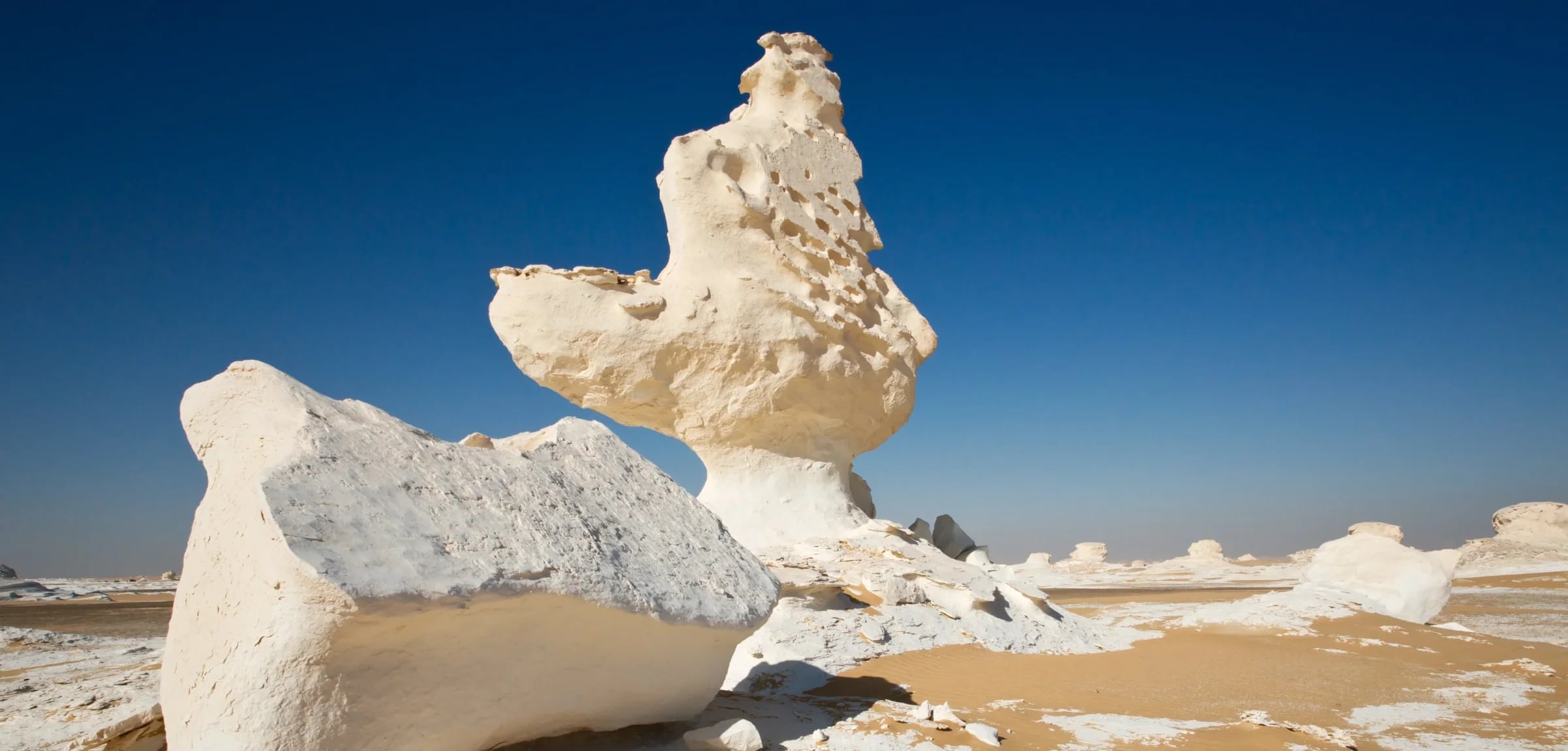 http://Formations%20rocheuses%20blanches%20sculptées%20par%20le%20vent%20dans%20le%20désert%20blanc%20sous%20un%20ciel%20bleu