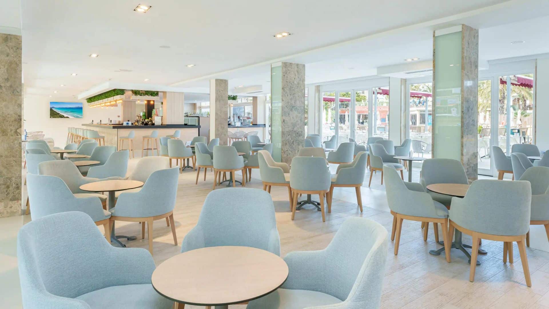 http://Salle%20de%20restaurant%20avec%20tables%20rondes%20et%20fauteuils%20clairs%20dans%20un%20hôtel%20contemporain