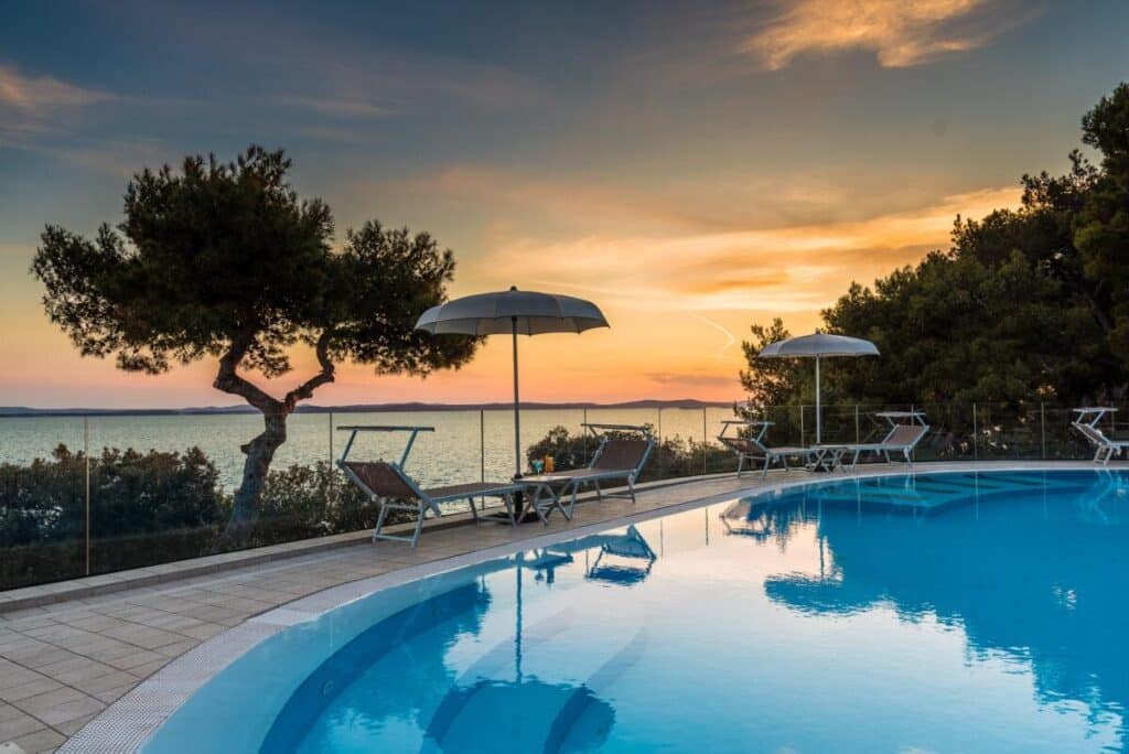 Piscine extérieure d’hôtel avec transats et vue sur la mer au coucher du soleil en Grèce