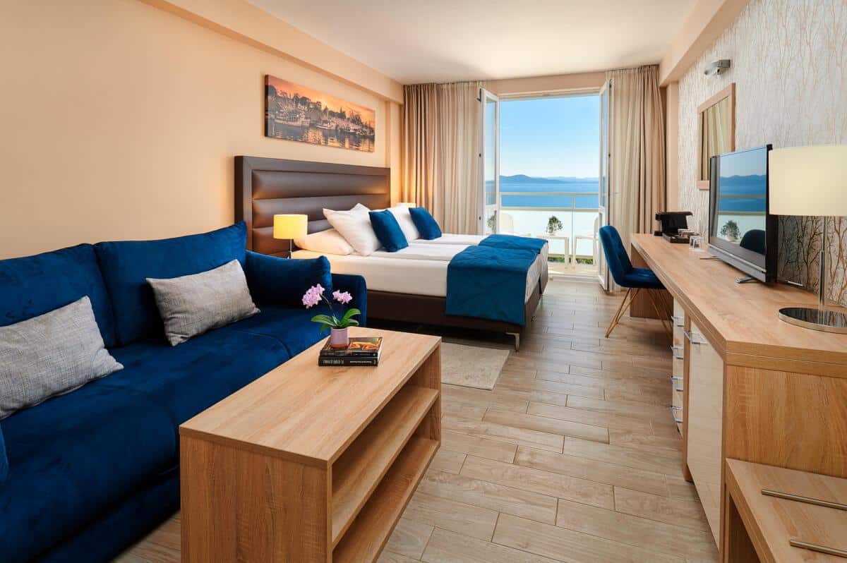 http://Chambre%20d’hôtel%20moderne%20avec%20lit%20double,%20canapé%20et%20vue%20sur%20la%20mer%20en%20Grèce