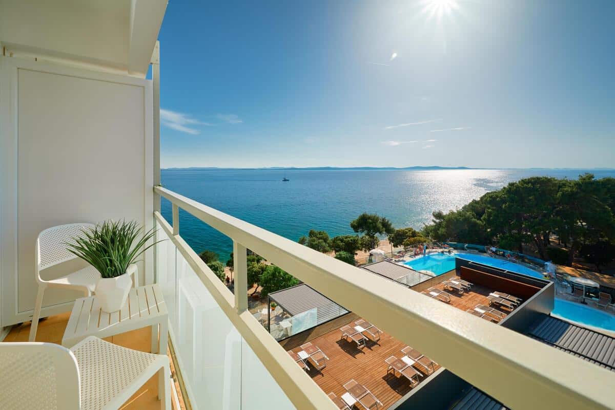 http://Balcon%20d’hôtel%20avec%20chaises%20et%20vue%20panoramique%20sur%20la%20mer%20et%20piscine%20en%20Grèce