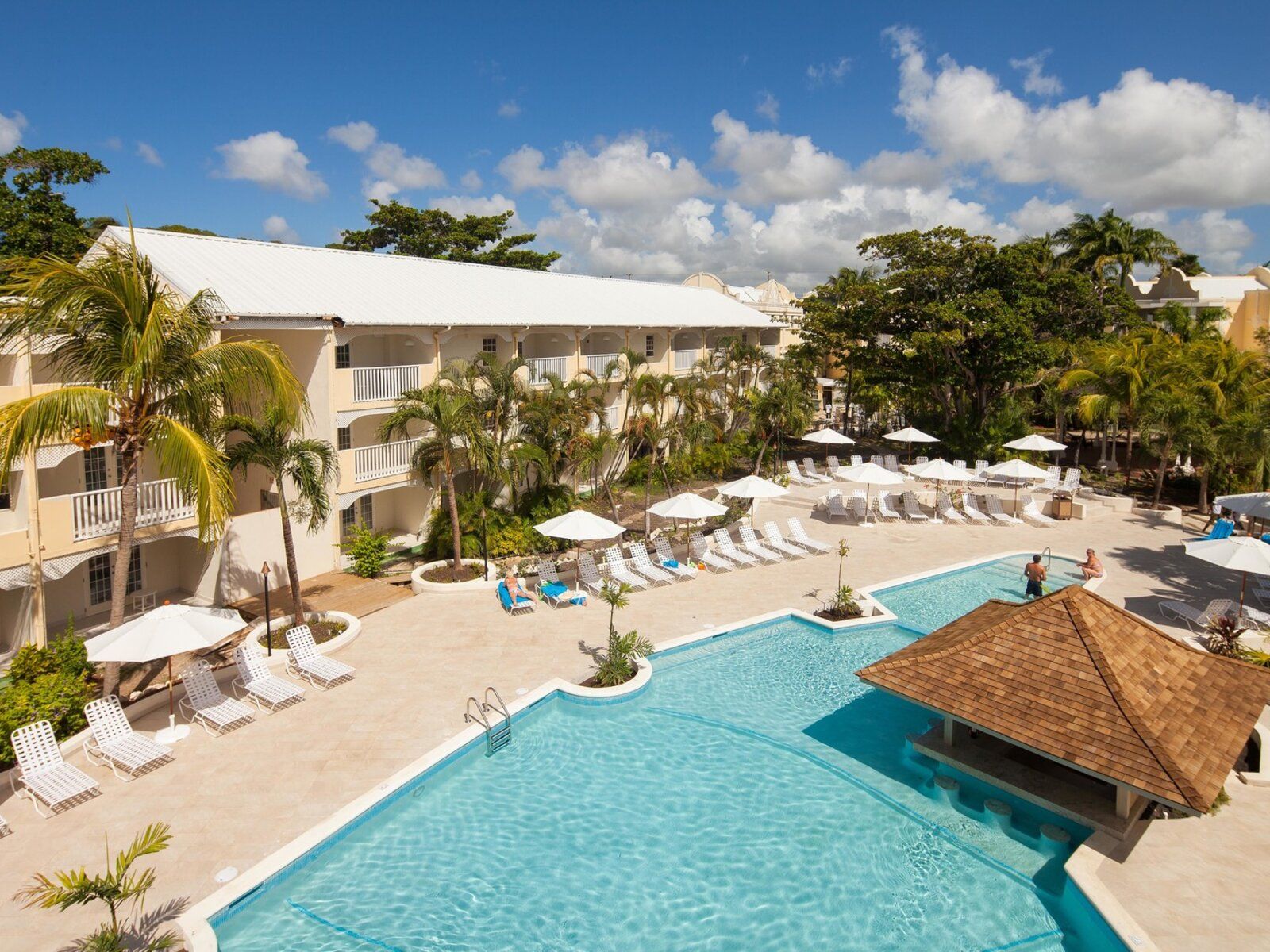 http://Piscine%20d’hôtel%20avec%20transats,%20parasols%20et%20palmiers%20dans%20un%20cadre%20tropical