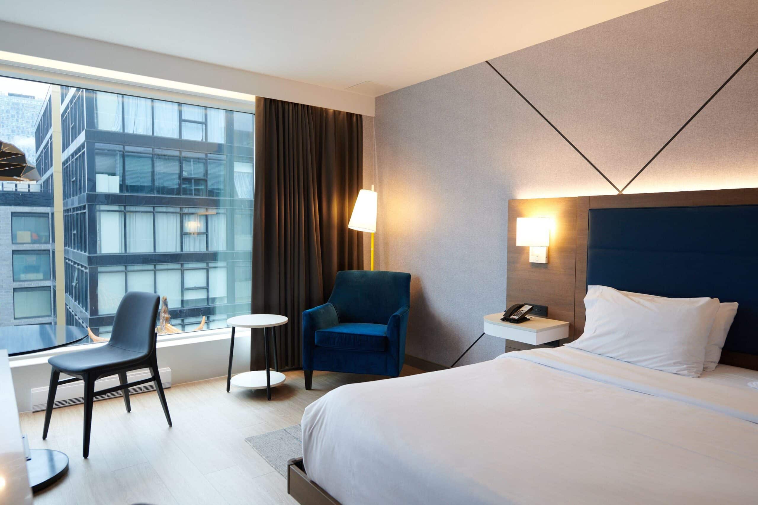 http://un%20hôtel%20à%20Montréal%20Chambre%20d'hôtel%20moderne%20avec%20lit%20double,%20fauteuil%20et%20grande%20fenêtre%20offrant%20une%20vue%20sur%20le%20centre-ville%20de%20Montréal.