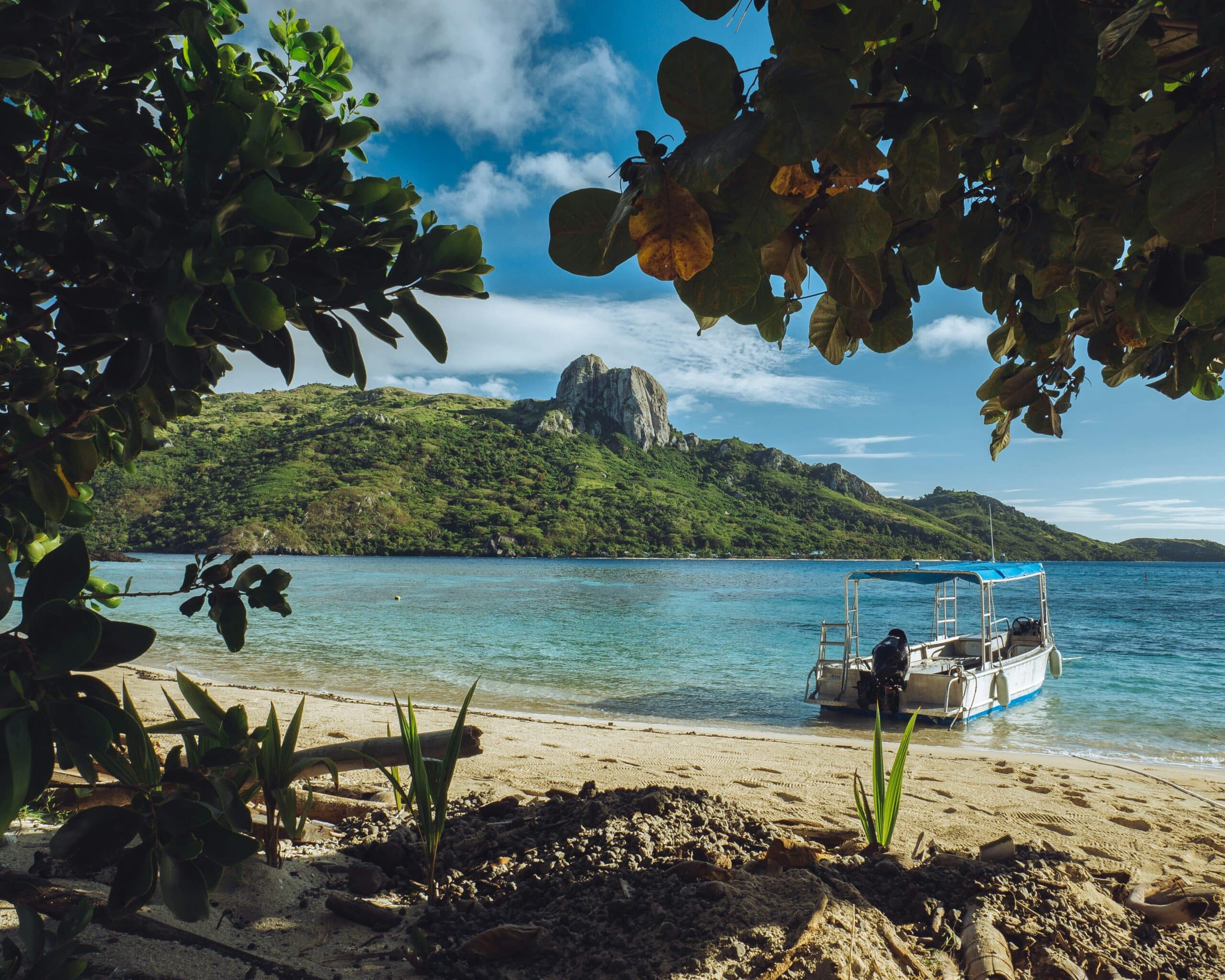 http://Petit%20bateau%20amarré%20sur%20une%20plage%20de%20sable%20blanc%20face%20à%20un%20lagon%20turquoise%20et%20une%20colline%20verdoyante%20aux%20îles%20Fidji.