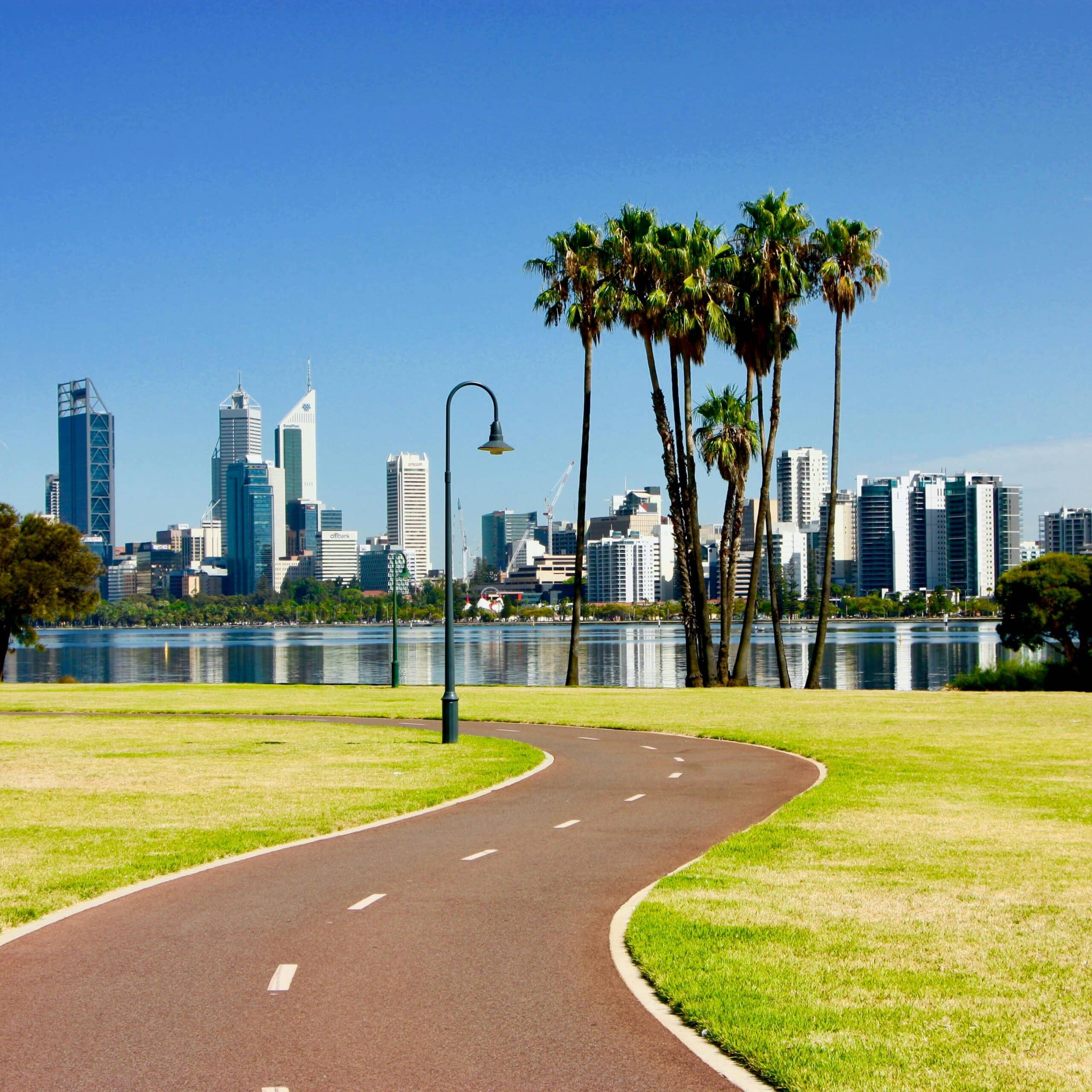 http://Vue%20sur%20une%20skyline%20moderne%20avec%20palmiers,%20promenade%20et%20plan%20d’eau%20au%20premier%20plan