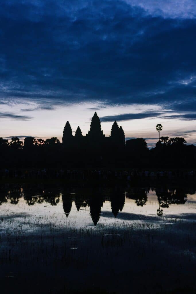 Silhouette d’Angkor Wat au Cambodge avec reflet dans l’eau sous un ciel sombre