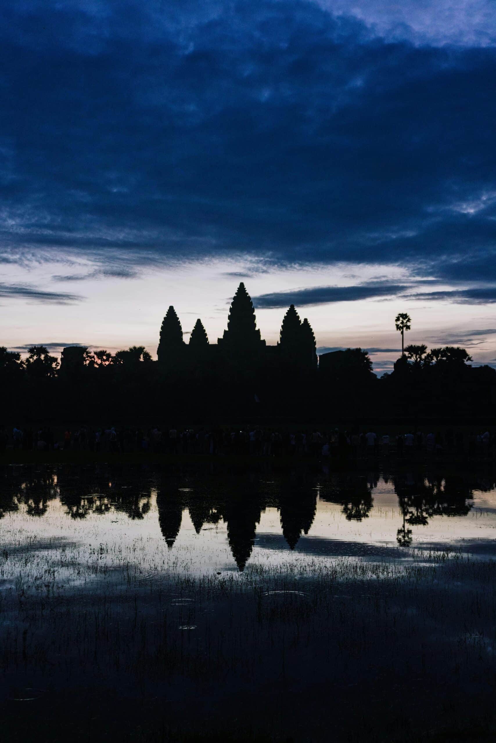 http://Silhouette%20d’Angkor%20Wat%20au%20Cambodge%20avec%20reflet%20dans%20l’eau%20sous%20un%20ciel%20sombre
