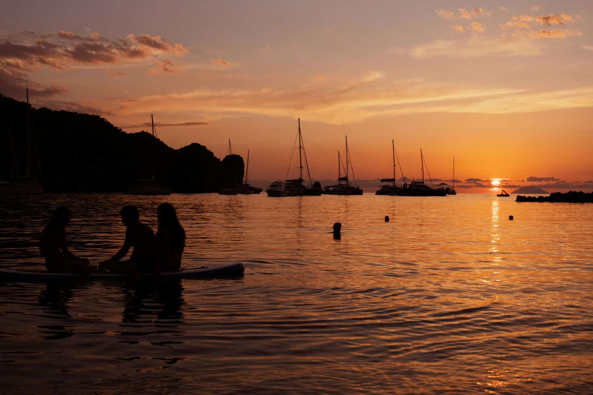 http://Silhouettes%20de%20bateaux%20et%20personnes%20dans%20l’eau%20au%20coucher%20du%20soleil%20sur%20la%20mer