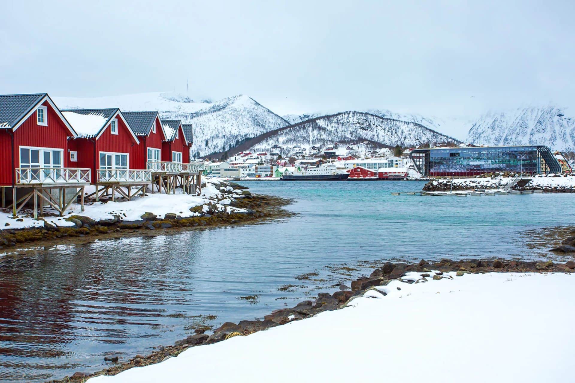 http://Maisons%20rouges%20sur%20pilotis%20au%20bord%20de%20l’eau%20dans%20un%20village%20enneigé%20des%20îles%20Lofoten