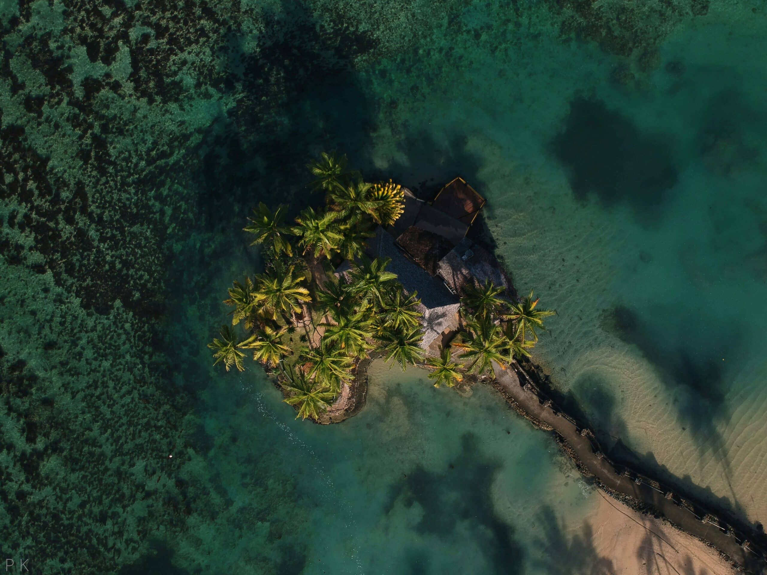 http://Vue%20aérienne%20d'un%20îlot%20bordé%20de%20palmiers%20entouré%20d'un%20lagon%20aux%20eaux%20turquoise.