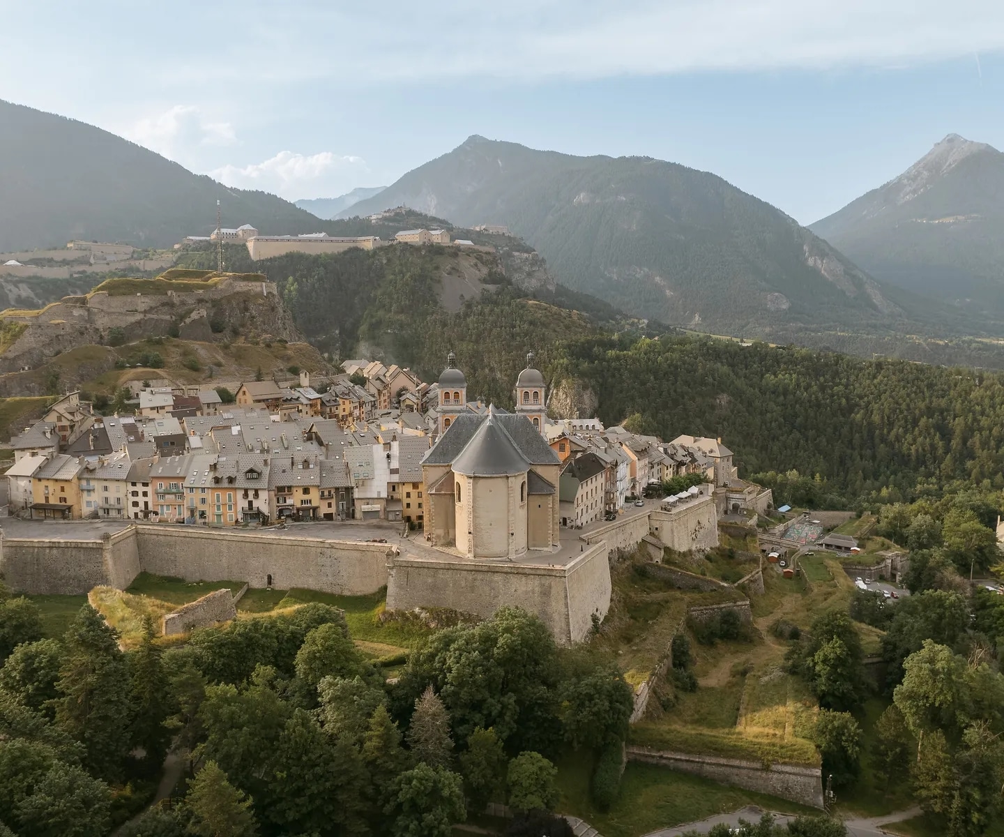 http://Vue%20aérienne%20d’un%20village%20fortifié%20en%20montagne%20entouré%20de%20forêts%20et%20de%20sommets%20alpins